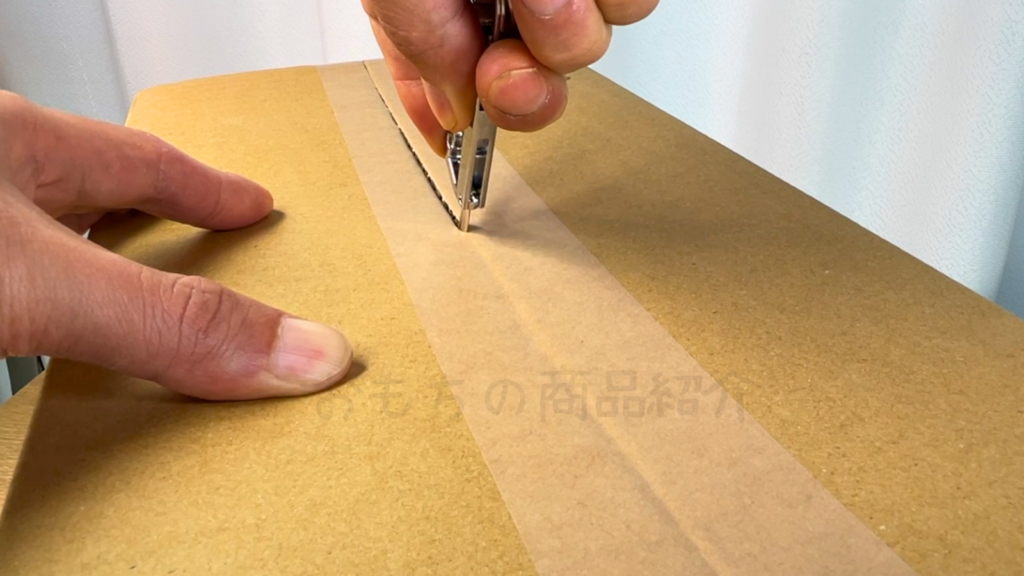 フックキーホルダーのツールで段ボールを開けている様子