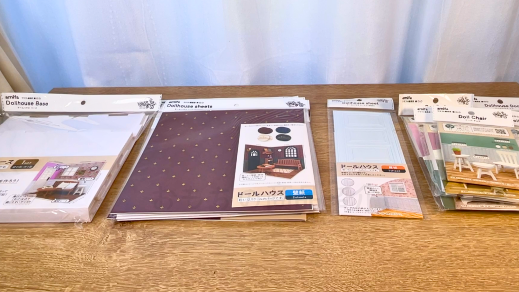 セリア|ドールハウスベースだけでなく、床材、壁紙、家具などの商品写真を机に並べた写真